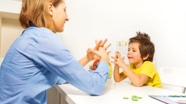 Boy exercises putting fingers with therapist
